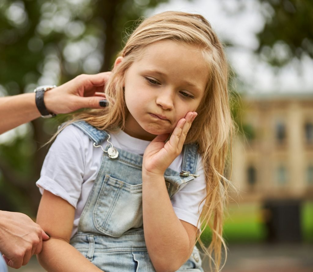 Female child holding hand on the face while feeling pain in the teeth