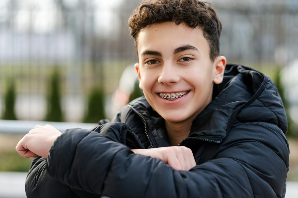 Happy boy, handsome teenager with braces looking at camera